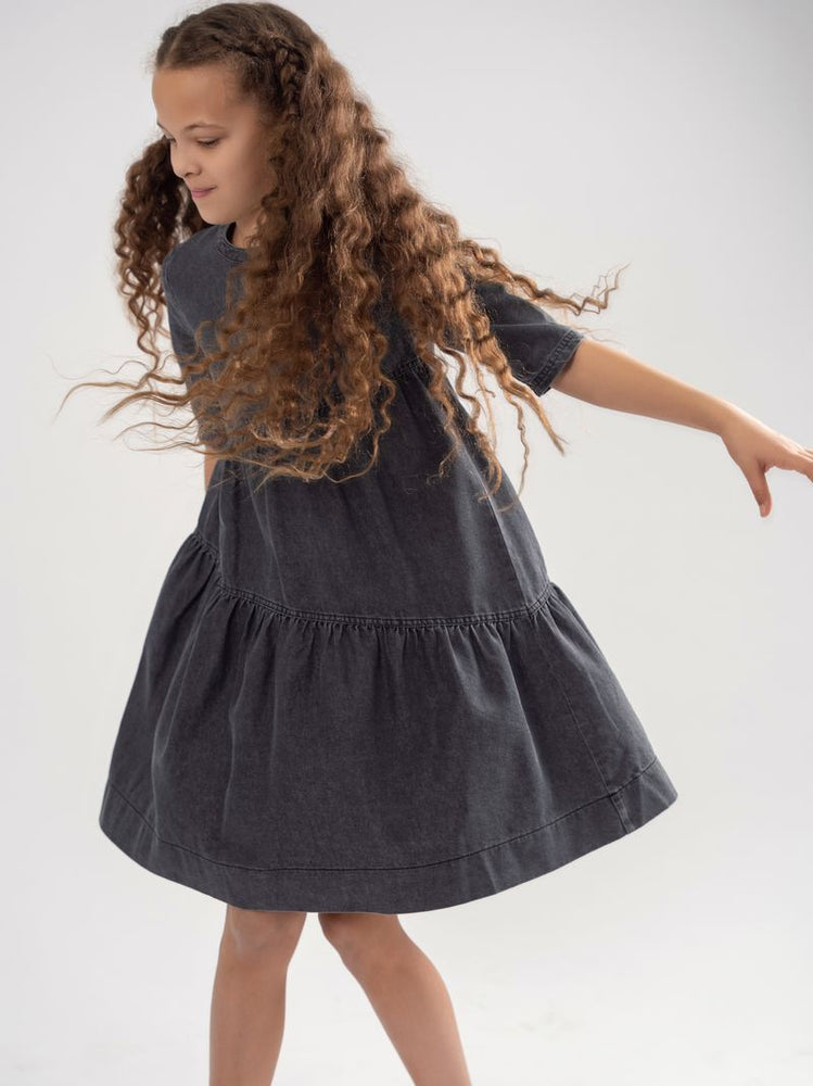 teela denim dress Meet our must-have Girls Denim Dress! This stylish dress features two oversized pockets and a chic collar, making it super cool and effortlessly fashionable. Available in classic blue wash denim